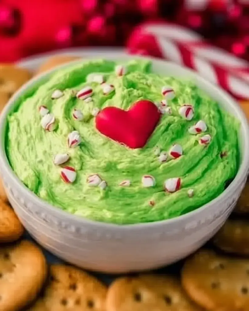 Colorful and festive Grinch Dip served in a green bowl with holiday decorations.